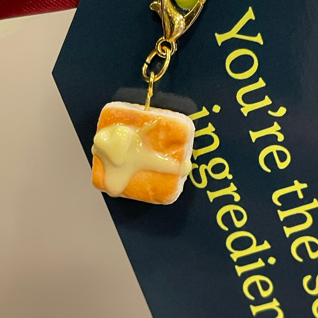 Small biscuit-shaped charm with yellow heart butter next to a gift tag.