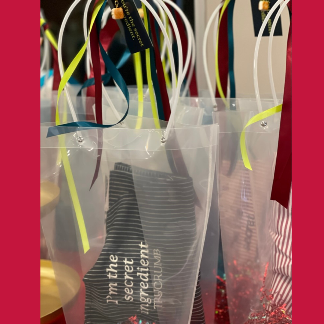 Gift bags with colorful ribbons and arpons labeled 'I'm the secret ingredient.'