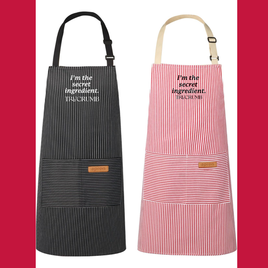 Two aprons, one black and one red and white striped, with I'm the Secret Ingredient text on each.