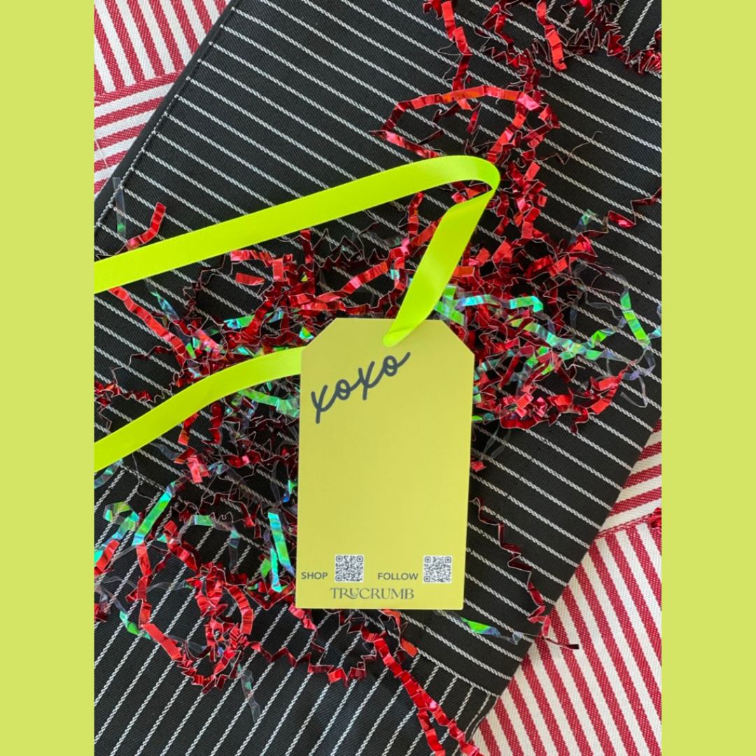 Gift with black and white striped aprons, red crinkle paper, and a tag saying 'You're the secret ingredient' on red and white striped aprons.