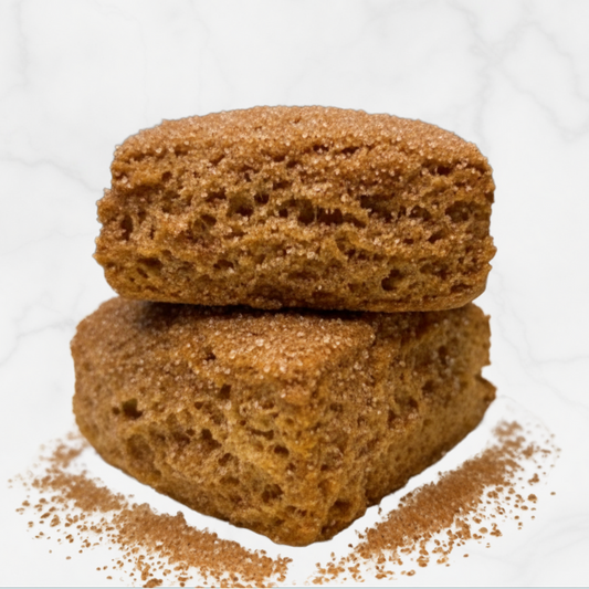 Two stacked TruCrumb gluten-free cinnamon maple biscuits with a dusting of cinnamon on a white background