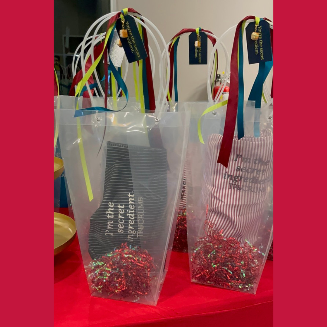 Gift bags with colorful ribbons and text on aprons a red tablecloth