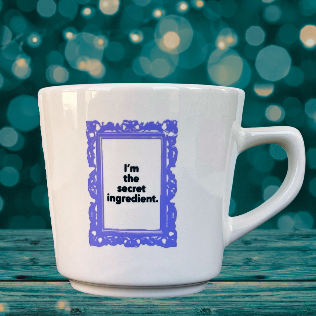 White mug with purple text on a teal background